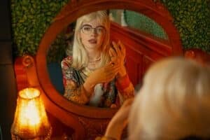 jeune femme avec une frange et des lunettes caroline abram se regardant dans un miroir