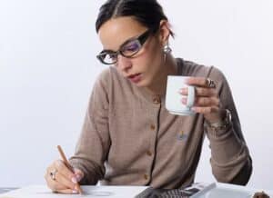 Femme concentrée travaillant sur des documents avec des lunettes de vue noires à monture épaisse