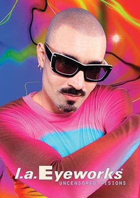 Color portrait of a person with a mustache wearing black sunglasses, against a psychedelic multicolored background with the text "l.a. Eyeworks uncensored visions".