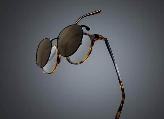 Round sunglasses with tortoiseshell frames floating on a gray background, highlighting the design and finesse of the temples.