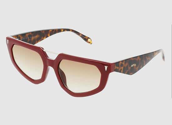 Vintage burgundy red sunglasses with thick frames, cream tinted lenses, tortoiseshell pattern on the inside of the temples and designer logo near the hinges.