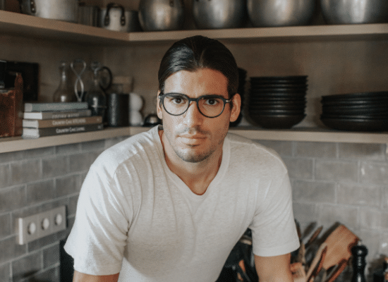 Man in a kitchen wearing Sea2see black-rimmed glasses and a serious expression.