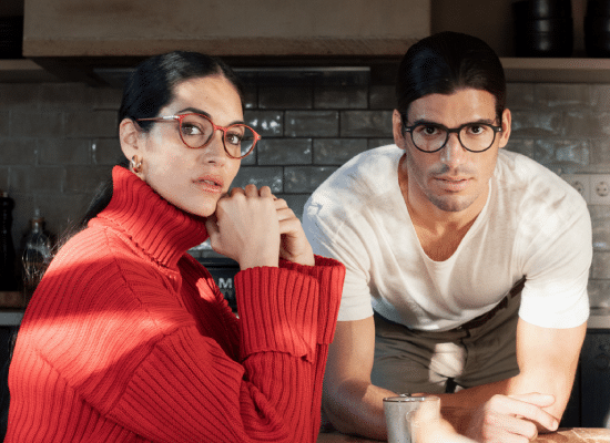 Man and woman in a kitchen, both wearing Sea2see glasses, the woman in a bright red jumper.